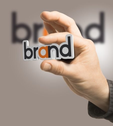 One hand holding the word brand over a beige background. Branding concept. The image is a composition between 2D illustration, 3D rendering and photography